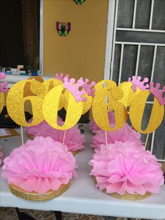 pink and gold cupcakes on a table with paper flowers in front of them