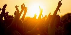 a group of people at a concert with their arms in the air and hands up