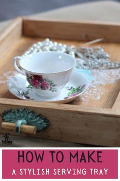 a teacup and saucer sitting on top of a wooden tray next to pearls