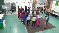 a group of children standing around each other in a room with bookshelves and desks