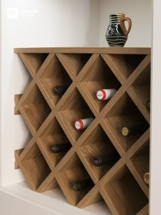 a wooden wine rack with many bottles on it and a vase sitting on top of it