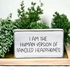 a wooden sign that says i am the human version of tangled headphones