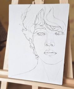 a drawing of a woman's face on a white paper with a wooden easel