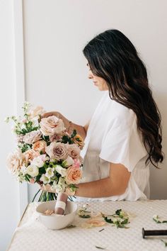 a woman arranging flowers on a table