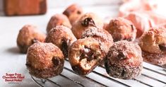 chocolate covered doughnut holes sitting on a cooling rack with one bite taken out and the other half eaten