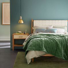 a bedroom with a bed, nightstand and green blanket on the bed in front of it