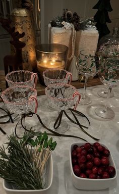 the table is set with wine glasses, cranberries and other holiday decor items