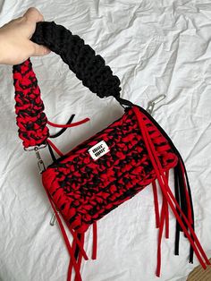 a hand holding a red and black purse