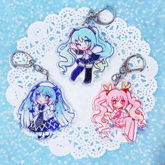 three keychains with anime characters on them sitting on a doily covered table