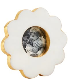 a white and gold flower shaped frame with a child in it