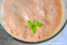 a smoothie is in a glass with a green leaf on top