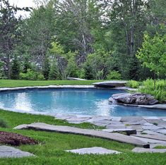 an outdoor swimming pool surrounded by stones and grass