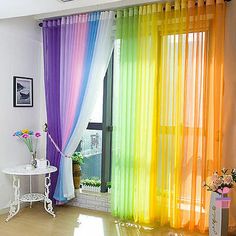 colorful curtains are hanging in front of a window with flowers on the table next to it