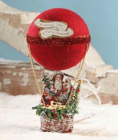 a christmas ornament with santa claus in a hot air balloon on top of snow