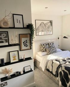 a bed sitting in a bedroom next to a wall filled with pictures and framed art