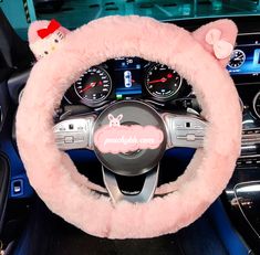 a pink steering wheel cover with hello kitty on the front and center console in a car