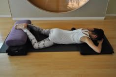 a woman is laying on her stomach on a yoga mat