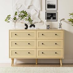 a dresser with plants and pictures on the wall