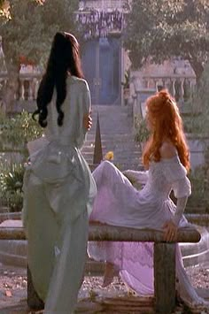 two women in white dresses sitting on a bench