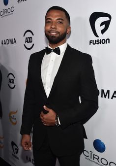 a man in a tuxedo standing on a red carpet