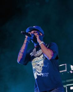 a male in a blue shirt and hat is holding a microphone up to his mouth