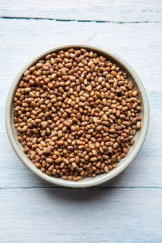 a white bowl filled with brown lentils on top of a blue wooden table