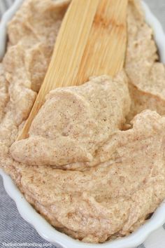 a wooden spoon in a white bowl filled with peanut butter