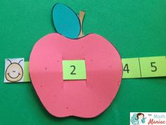 an apple cut in half on a green surface with tape and numbers to match it