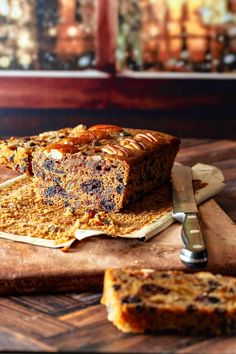 a loaf of fruitcake sitting on top of a wooden cutting board