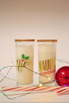 two shot glasses sitting on top of a table next to a christmas ornament