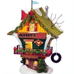 a christmas ornament with a tree house on it's side and a tire hanging from the roof