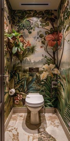 a toilet in a bathroom with tropical wallpaper and floor to ceiling murals on the walls