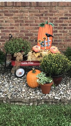 an assortment of pumpkins and gourds are arranged in front of a brick wall