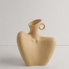 a beige vase sitting on top of a white table