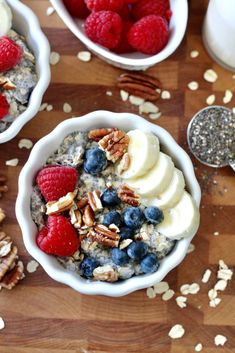 two bowls filled with oatmeal and fruit on top of a wooden table