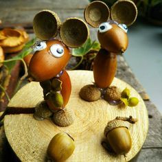 two figurines made to look like acorns are sitting on a piece of wood