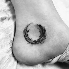 a black and white photo of a person's foot with a circle tattoo on it