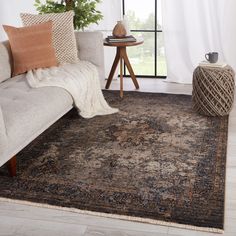 a living room area with a couch, coffee table and rug in front of a window