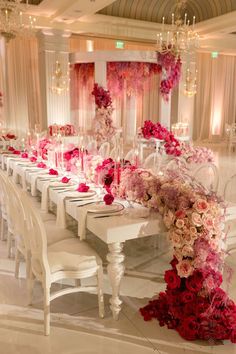 a long table with white chairs and pink flowers on the top is set for a formal dinner