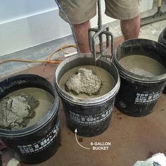 three buckets are filled with cement and one has a shovel in it