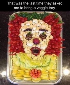 a plastic container filled with fruit and veggies that has a face made out of vegetables