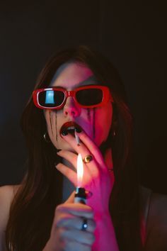 a woman wearing sunglasses holding a lighter in her hand