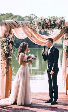 a bride and groom standing under an arch with flowers