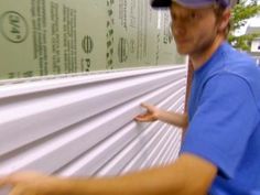 a man in blue shirt and cap working on roofing material with hand held out to the side