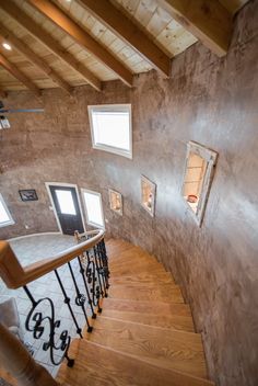 a spiral staircase in a home with wood floors and windows on the wall, leading up to the second floor