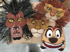 three paper masks with different faces and hair on them, one has an animal's head