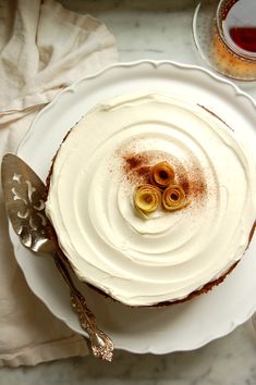 a white plate topped with a cake covered in frosting and two olives on top of it