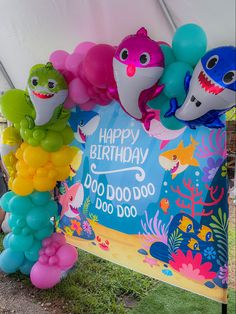 there are many balloons in the shape of sharkes on this birthday party sign that says happy birthday do do do do do