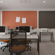 an office with multiple desks and computers in it's cubicle, along with orange walls