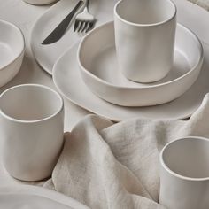 a table set with white dishes and silverware